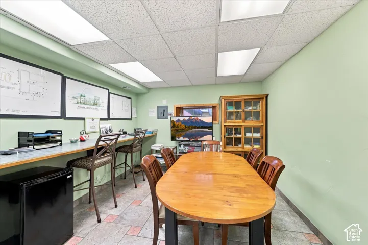 Recessed lighting with grid ceiling, built-in counter space, tiled flooring, and a built-in wooden display cabinet