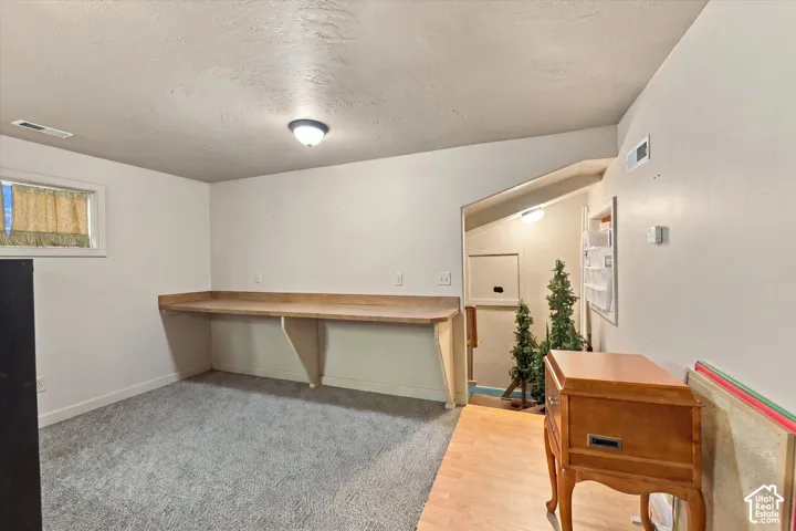 Built-in desk area with wood-finish countertop, carpeted flooring, and a window