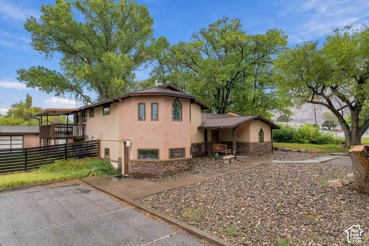 Stucco exterior with stone accents, covered entry, second-story balcony, and gravel landscaping
