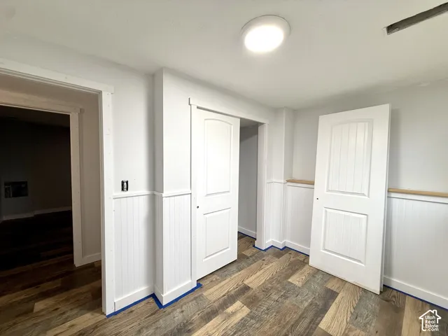 Wood-finish flooring with white wainscoting and a natural wood cap
