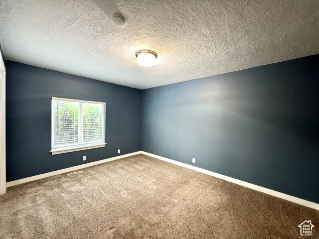 Recessed window with blinds, dark accent wall, and textured ceiling