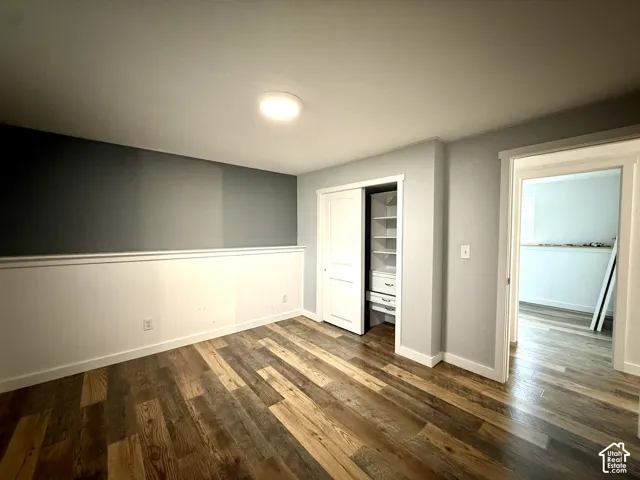 Wood-finish flooring, built-in closet shelving, two-tone wall treatment, and overhead lighting