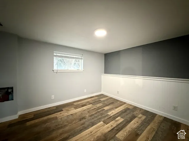 Wood-finish flooring, recessed ceiling lighting, a window with blinds, and white wainscoting