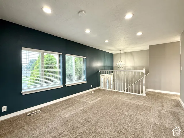 Carpeted room featuring recessed lighting and a decorative chandelier