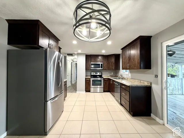Kitchen featuring dark wood-finish cabinetry, stainless steel appliances, tile flooring, and a sliding glass door to an exterior deck