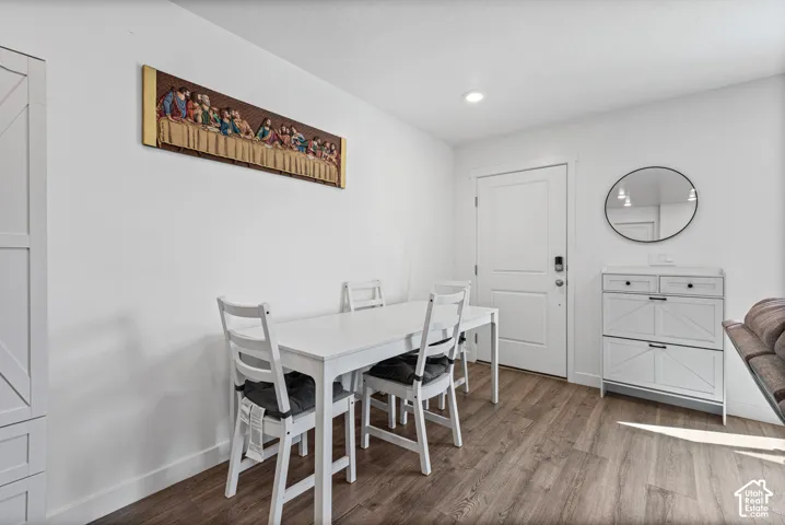 Wood-finish flooring, recessed lighting, and a white interior door with dark hardware