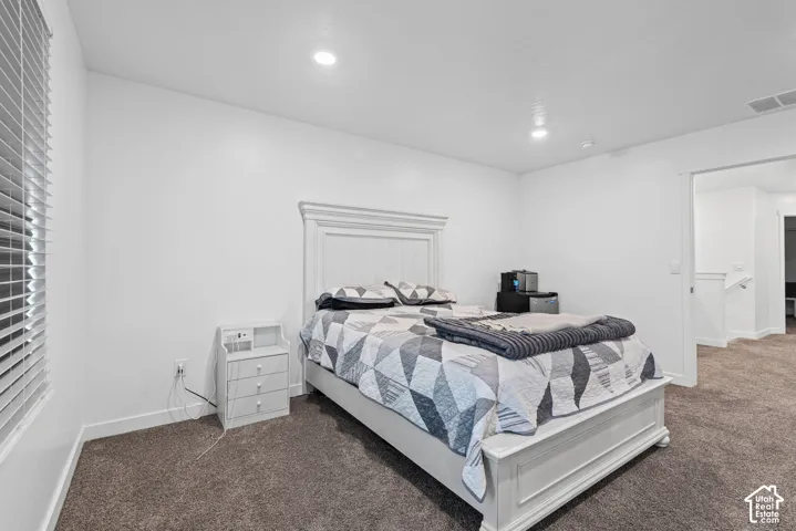 Recessed lighting, white walls, textured carpeting, window with blinds, and white trim