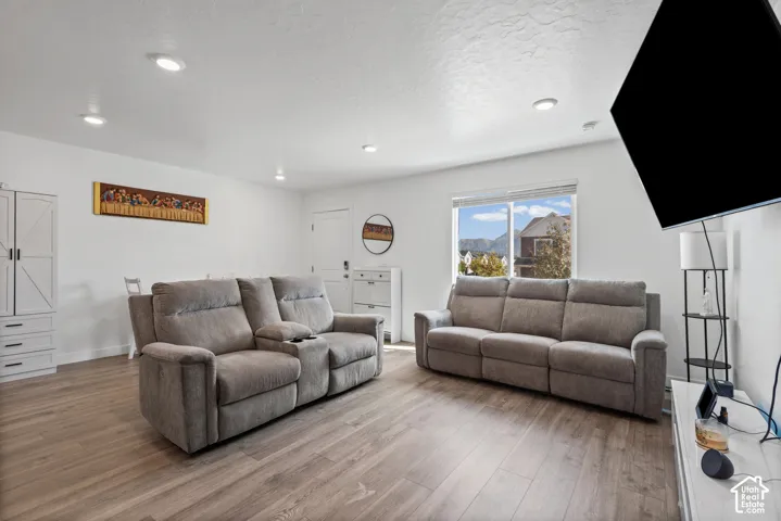 Recessed lighting, wood-finish flooring, white walls, and a large window