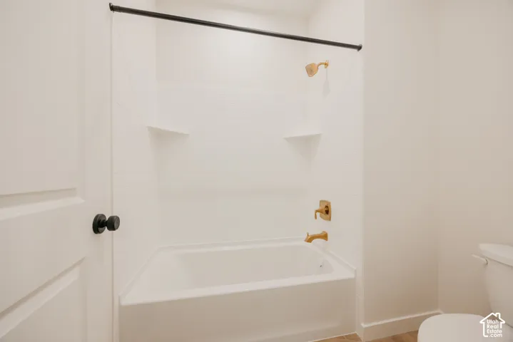 White subway tile shower surround with integrated corner shelves, brass fixtures, and a matte black shower rod