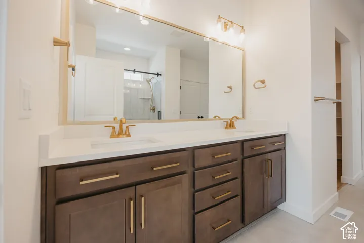 Dual vanity with wood-finish cabinetry, white countertop, and gold-tone fixtures