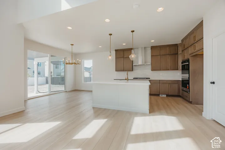 Open-concept kitchen with wood-finish flooring, a central island, recessed lighting, and integrated appliances