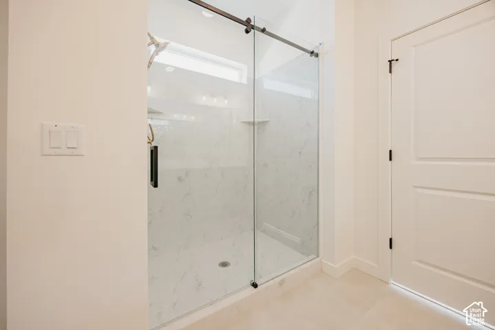 Walk-in shower with clear glass enclosure, a sliding barn-style door, and white marble-look wall tiling