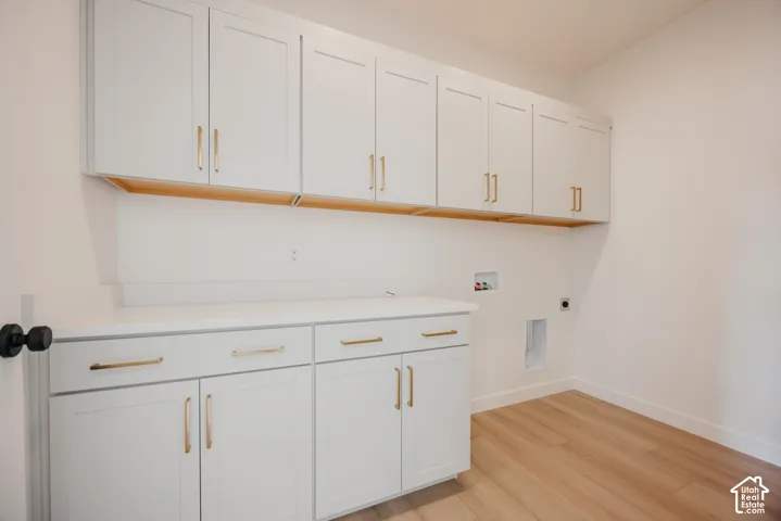 White shaker-style cabinetry with gold-tone hardware, wood-finish flooring, and white countertops