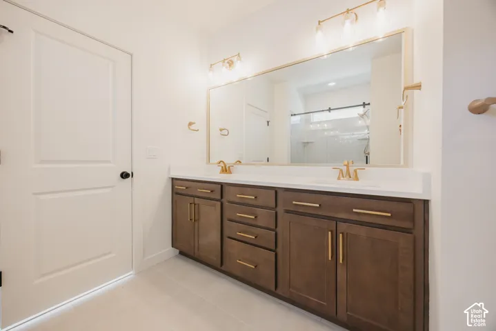 Double vanity with wood-finish cabinetry, white countertops, and gold-toned fixtures