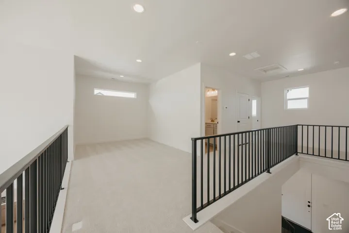 Carpeted landing with modern black metal railings, recessed lighting, and multiple windows