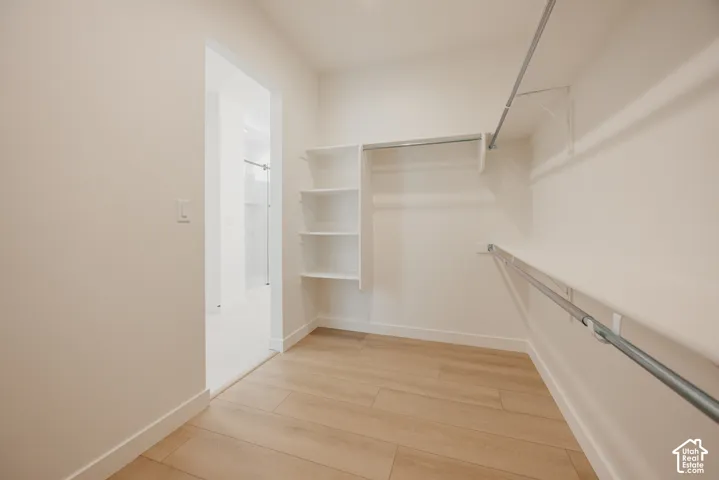 Walk-in closet with integrated shelving, multiple hanging rods, and wood-finish flooring
