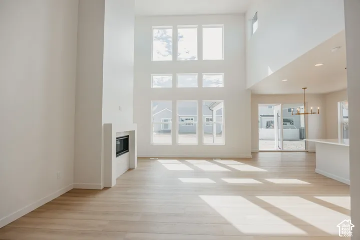 Spacious living area featuring a fireplace, wood-finish flooring, high ceilings, large windows, and an open-concept layout