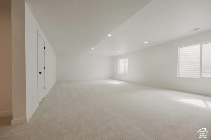 Spacious room featuring light-toned carpeting, recessed lighting, and multiple windows with white blinds