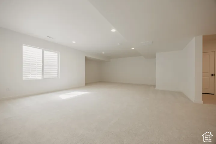 Expansive carpeted room featuring recessed lighting, a large window, and light-toned walls