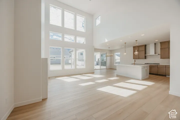 Soaring ceilings with extensive window arrangement, wood-finish flooring, recessed lighting, kitchen island with pendant lighting, and stainless steel range hood