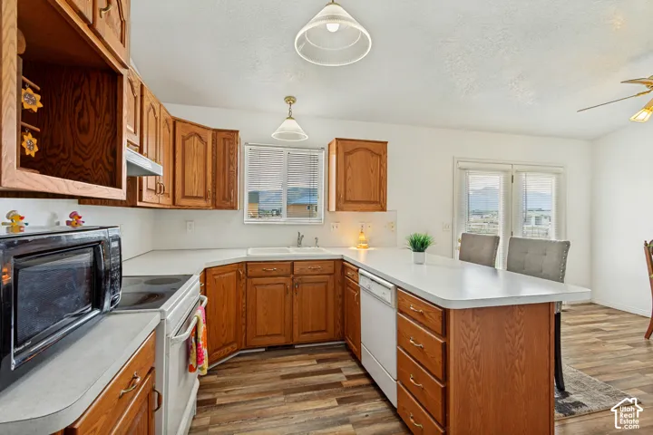 Wood-finish flooring, wood cabinetry, white countertops, built-in dishwasher, and French doors