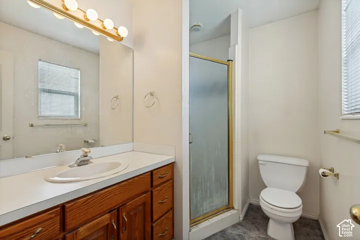Bathroom featuring a wood-finish vanity, white countertop, and a shower with a gold-toned frame