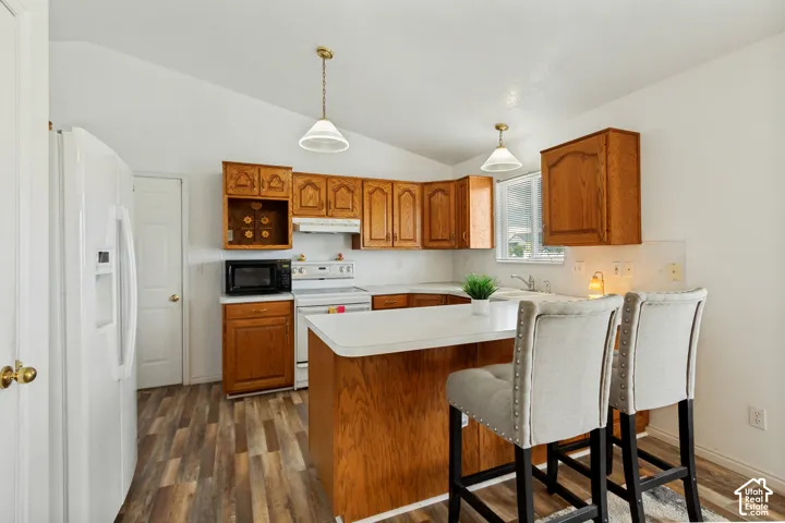 Kitchen featuring wood-finish flooring, wood cabinetry, white countertops, and white appliances