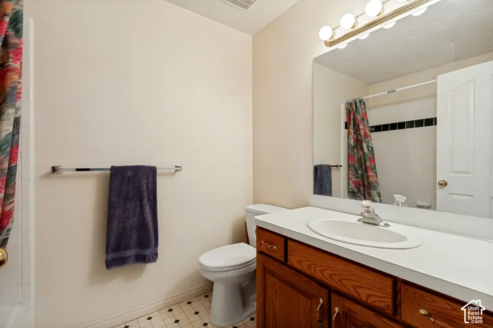 Bathroom featuring a wood-finish vanity with an integrated sink, a wall-mounted mirror, and a three-bulb vanity light fixture