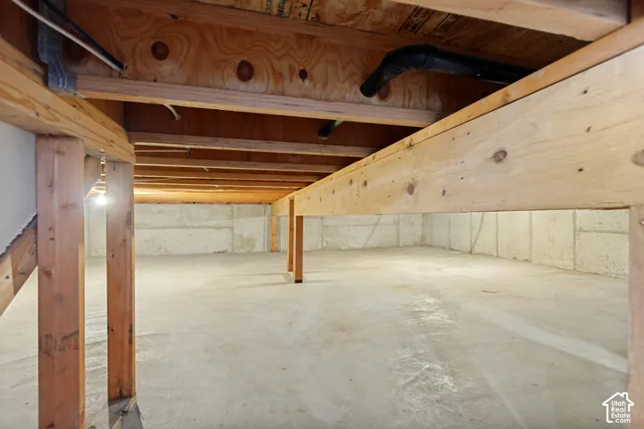 Unfinished basement with concrete floor and exposed wood ceiling joists