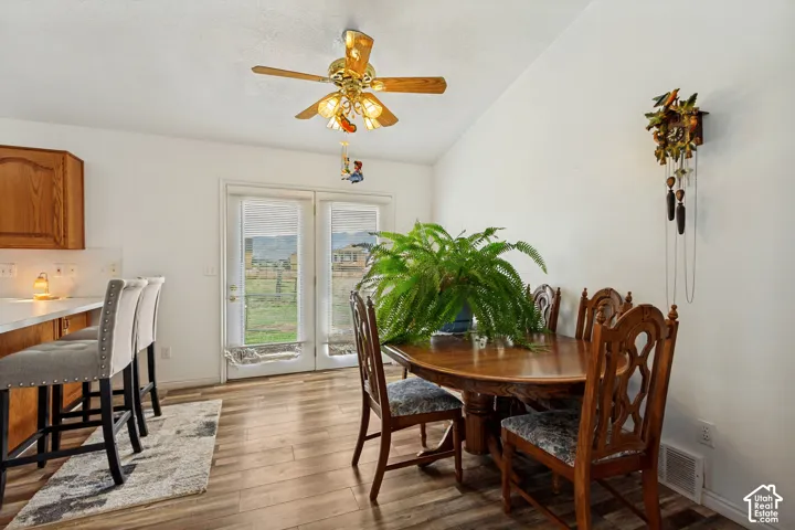 Wood-finish flooring, white walls, and a vaulted ceiling with a ceiling fan