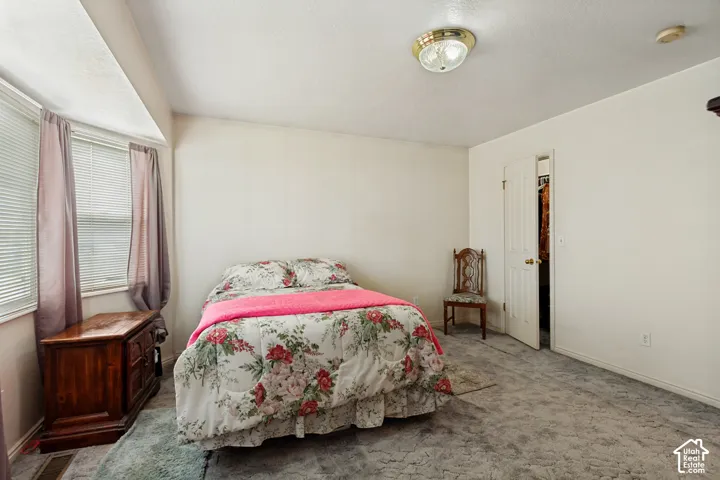 Recessed window with blinds, white paneled walls, gray carpet flooring, and a white interior door