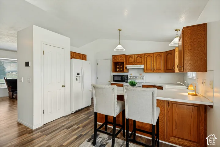 Kitchen featuring wood-finish flooring, wood cabinetry, white countertops, and white appliances