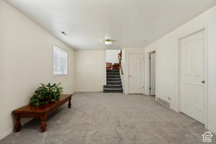 Wall-to-wall carpeting and neutral wall finishes create an inviting atmosphere, complemented by a prominent staircase with wood railing
