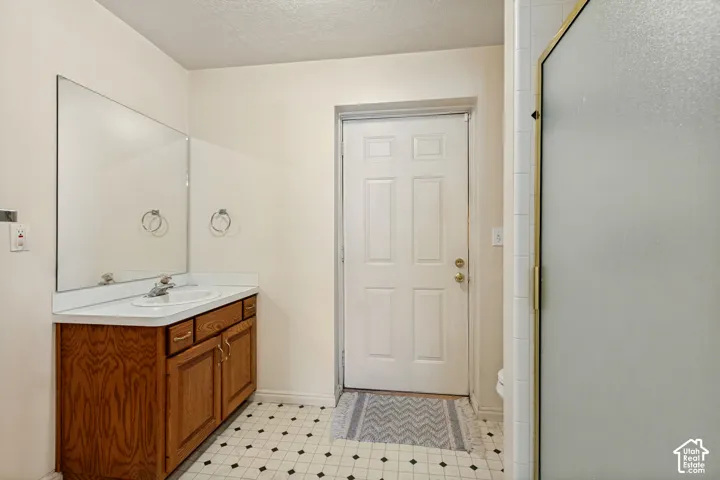 Double vanity with integrated sinks, wood-finish cabinetry, full-width mirror, and patterned floor tiling