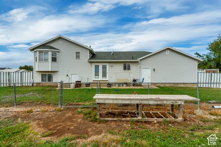 Rear exterior with light gray siding, white trim, bay window, and a chain-link fence