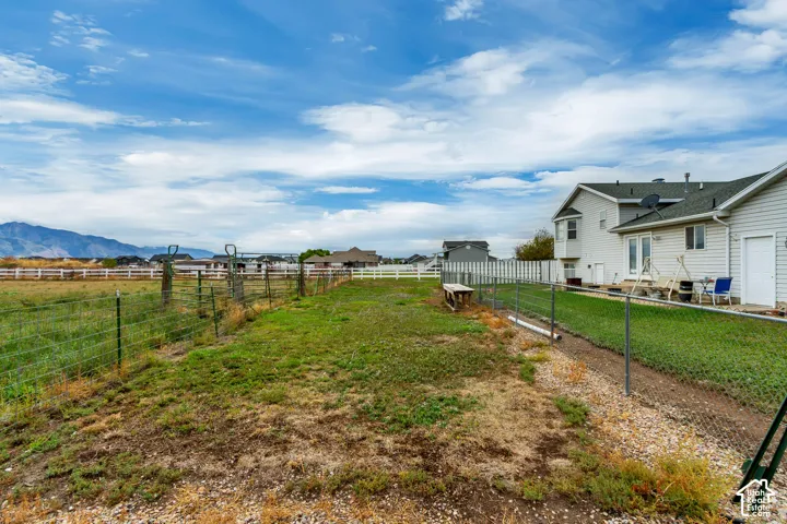 Expansive backyard featuring a chain-link fence, green lawn, and mountain backdrop