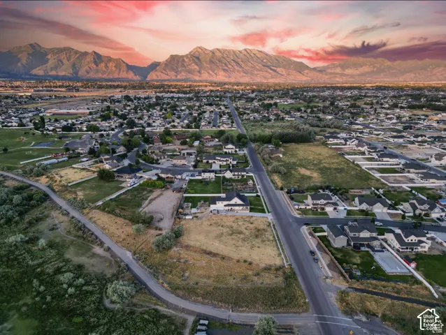 Expansive mountain backdrop with a residential community, open land parcels, and paved roads