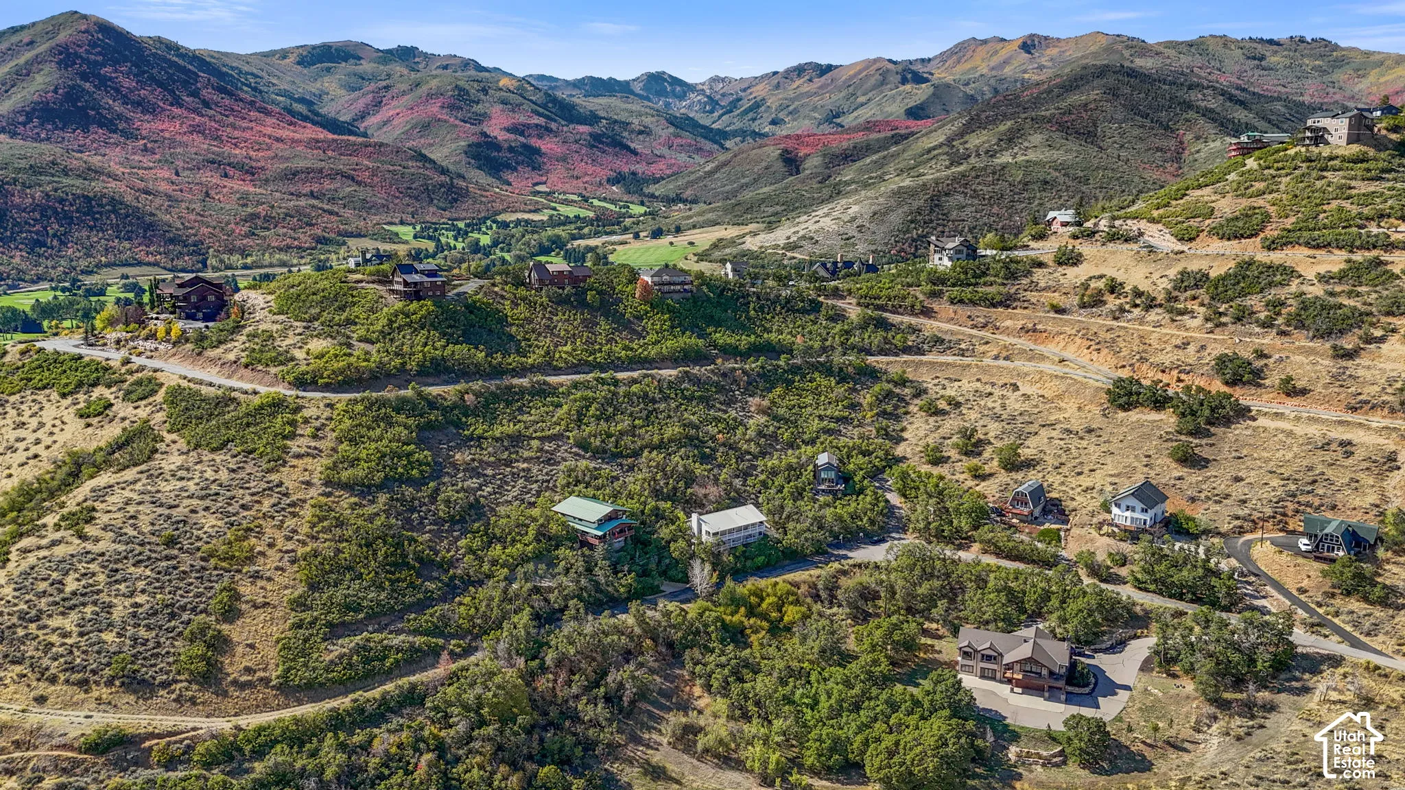 Expansive mountainous terrain featuring scattered residential properties, paved roadways, and varied natural vegetation