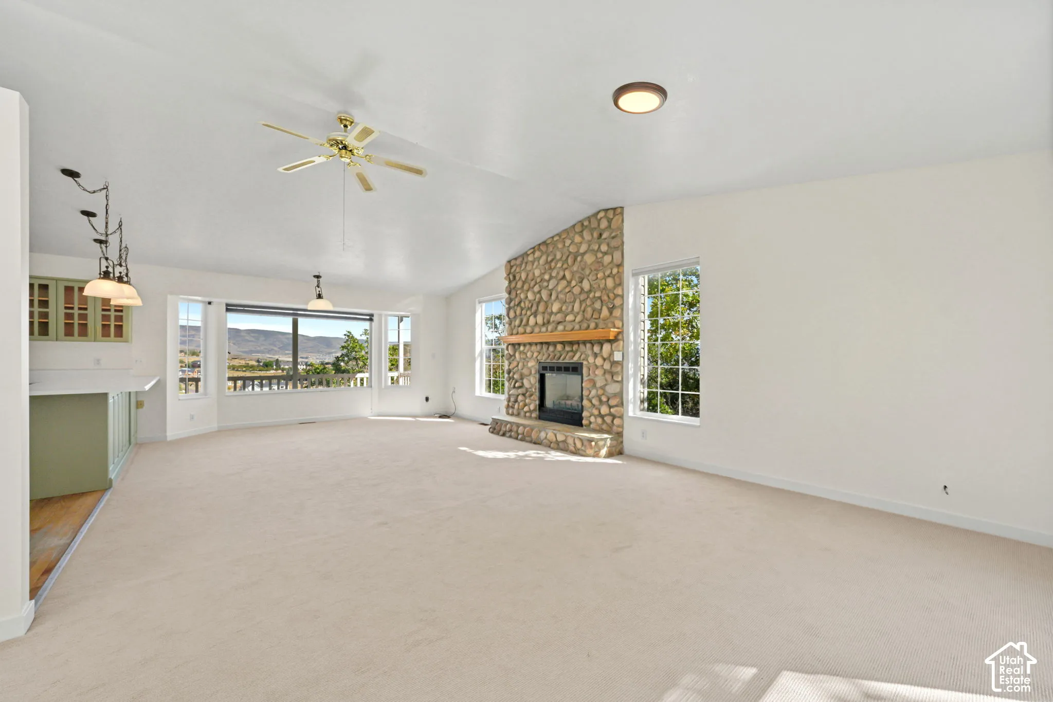 Spacious room featuring a stone-clad fireplace with a wood mantel, multiple large windows, and a built-in wet bar with cabinetry