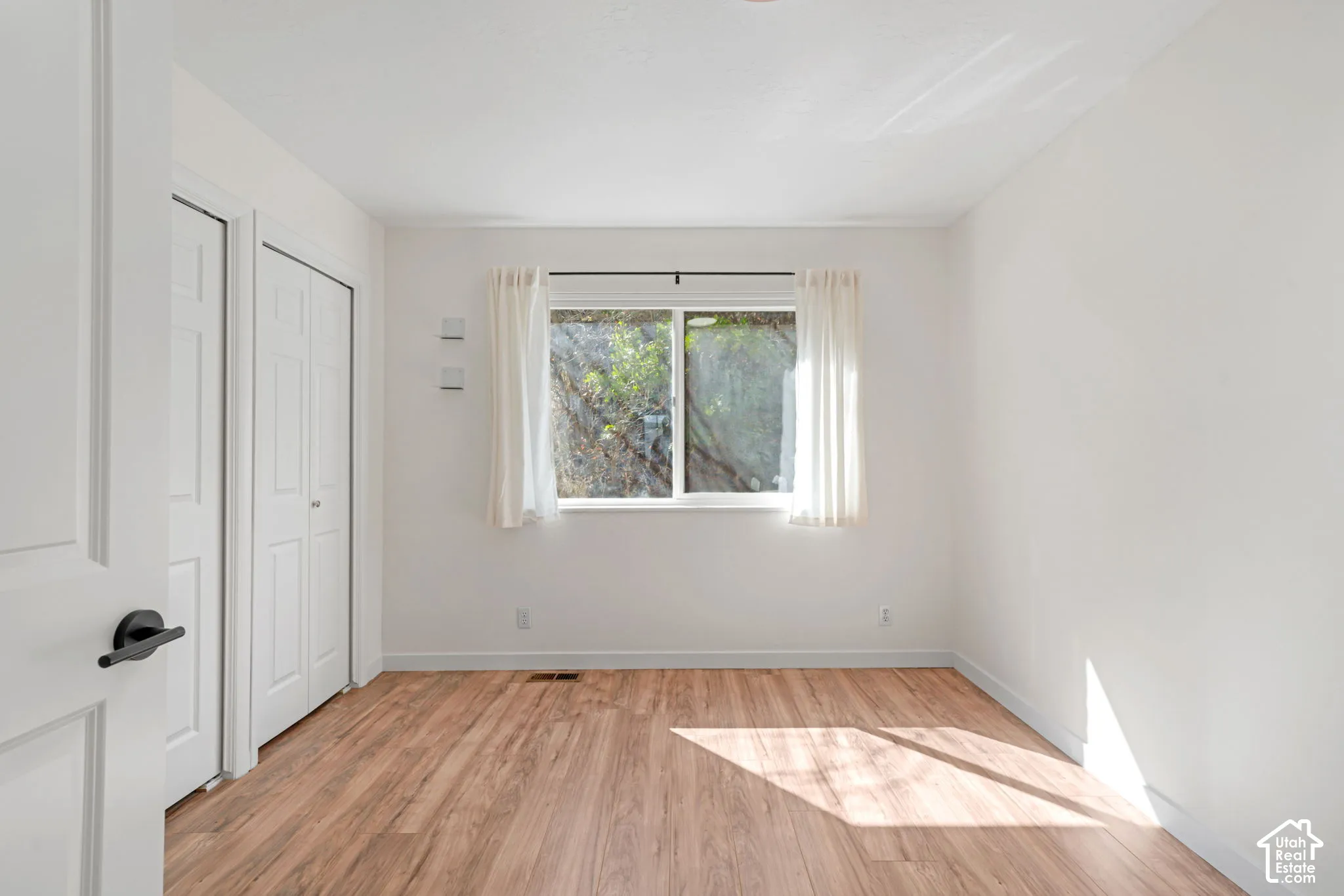 Wood-finish flooring, white walls, and a window with natural light