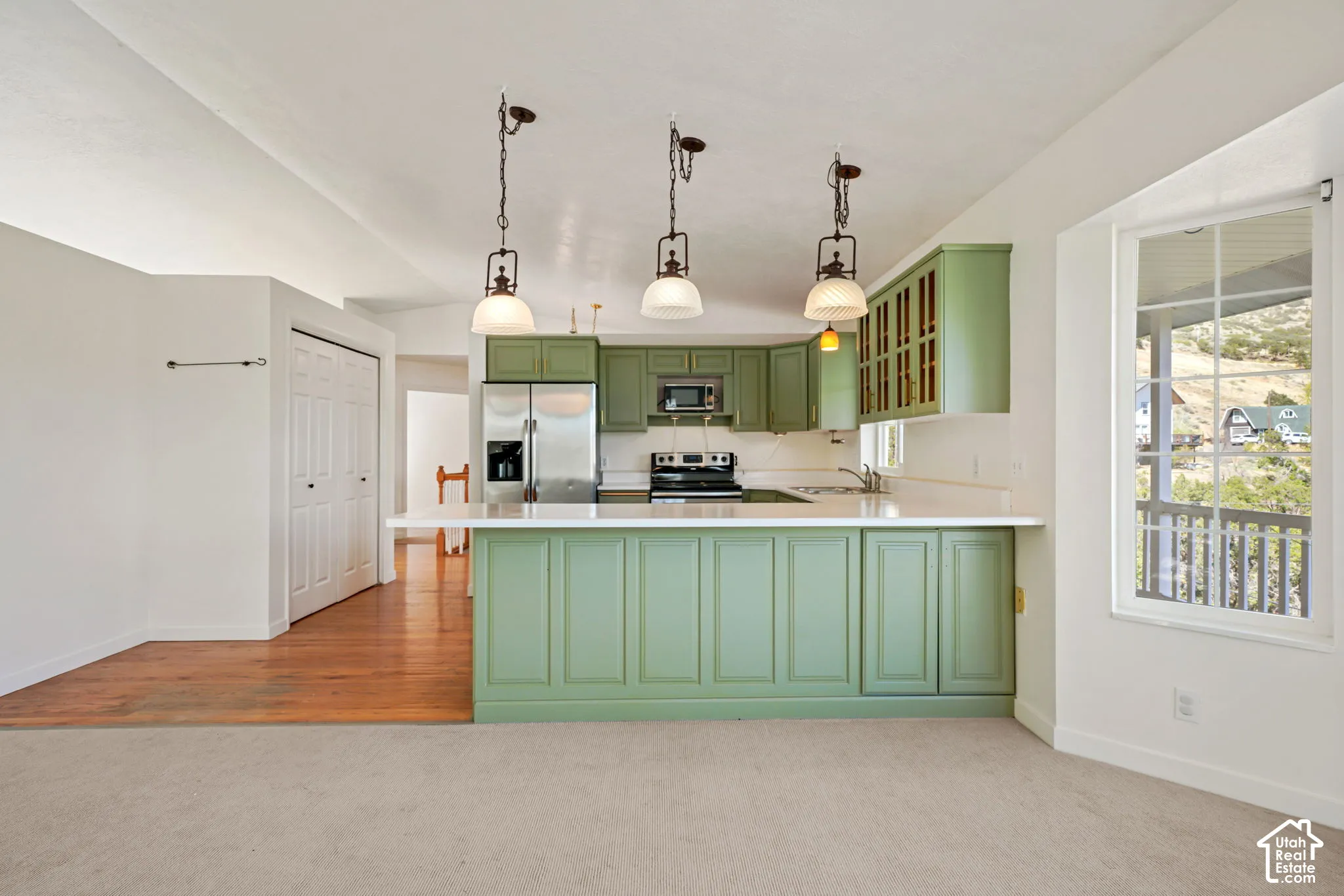 Kitchen featuring painted cabinetry, a peninsula with counter seating, stainless steel appliances, and a window overlooking a mountainous backdrop