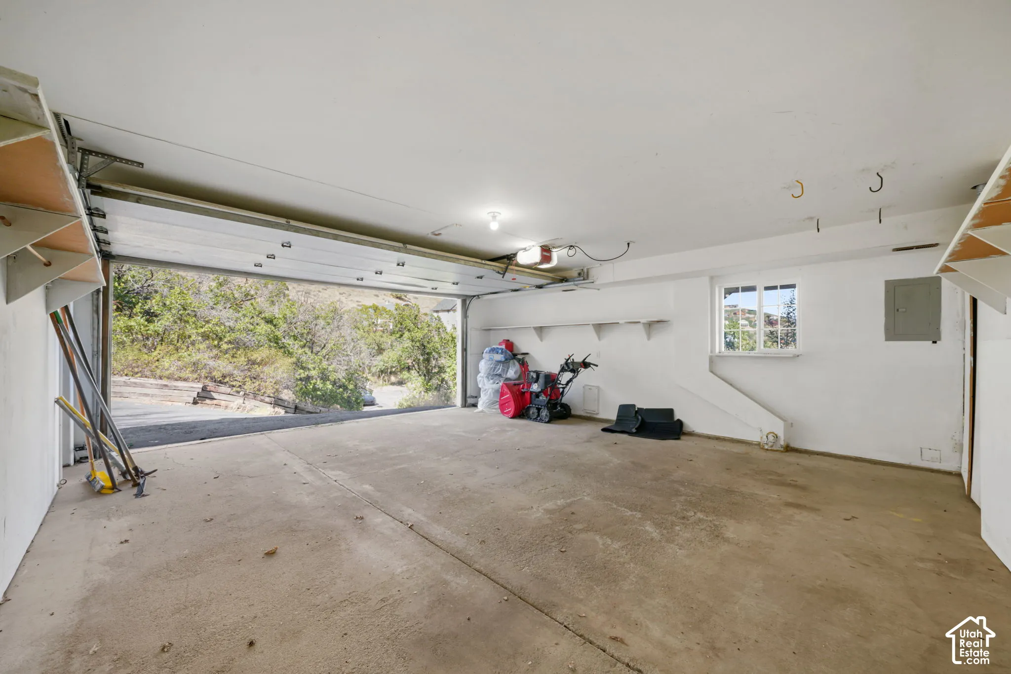 Spacious garage featuring a concrete floor, built-in shelving, a window, and an automatic garage door opener