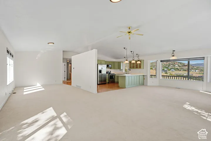 Open-concept living area with carpeting, recessed lighting, and a ceiling fan