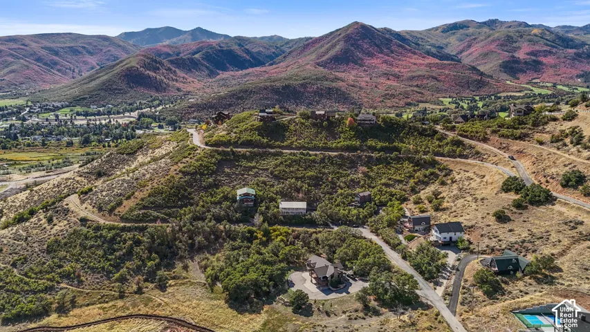 Mountainous terrain with natural landscaping, visible residential structures, and paved roadways