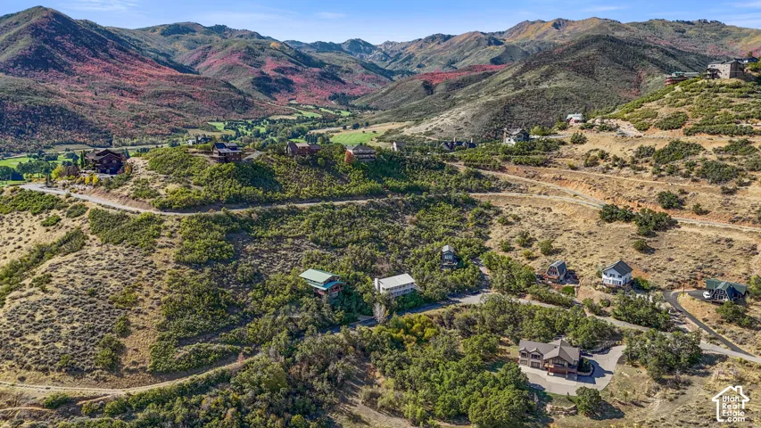 Expansive mountainous terrain featuring scattered residential properties, paved roadways, and varied natural vegetation