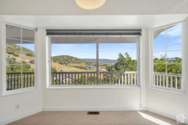 Bay window framing extensive hillside scenery, featuring a prominent central window with roller shades, flanked by two side windows with gridded panes