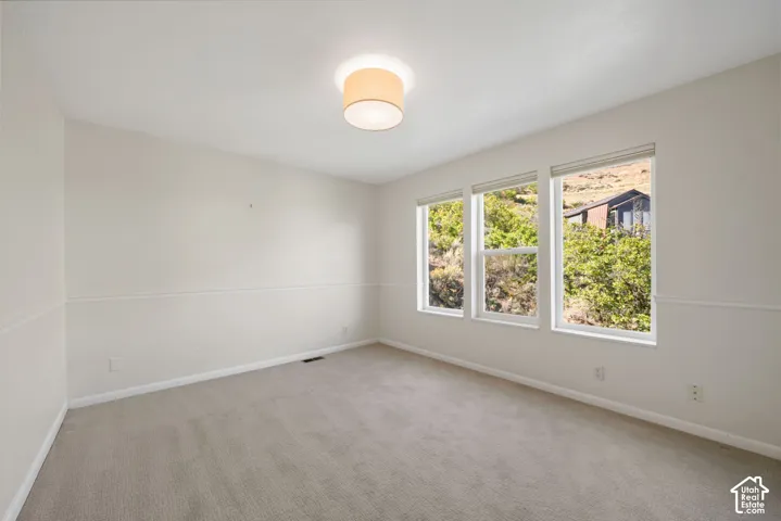 Light-filled room featuring a vaulted ceiling, recessed lighting, and three large windows