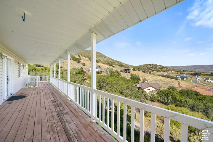 Expansive outdoor deck featuring wood-finish flooring and a white railing system