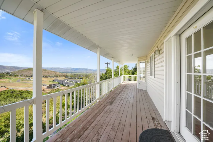 Expansive covered deck with wood-finish flooring, white railing, and multiple support columns