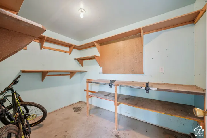 Built-in shelving, pegboard, concrete flooring, and a workbench with integrated vises connected to garage